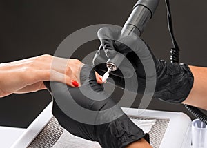 The master of the manicure saws and attaches a nail shape during the procedure of nail extensions in the beauty salon.