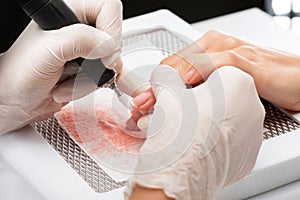 The master of the manicure saws and attaches a nail shape during the procedure of nail extensions in the beauty salon.