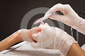 The master of the manicure saws and attaches a nail shape during the procedure of nail extensions in the beauty salon.