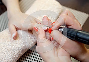 The master of the manicure saws and attaches a nail shape during the procedure of nail extensions with gel