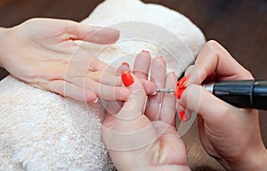 The master of the manicure saws and attaches a nail shape during the procedure of nail extensions with gel in the beauty salon