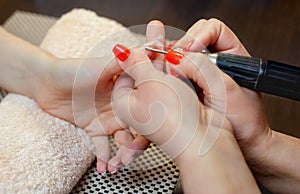 The master of the manicure saws and attaches a nail shape during the procedure of nail extensions with gel in the beauty salon.