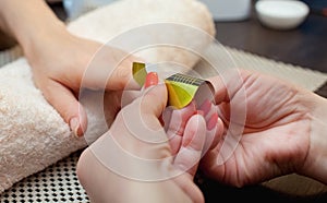 He master of the nail polish puts a fixative on the finger before making the nails gel in the beauty salon.