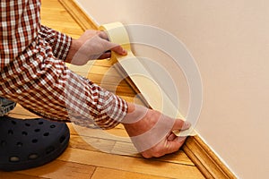 Master painter glues the masking tape on the baseboard