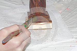 The master paints a piece of wood with a color impregnation brush