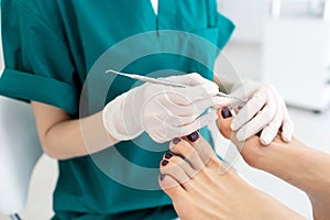 Master during a pedicure. The process of professional pedicures. The masked wizard prepares a special tool for nails to apply gel