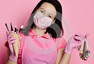 Master in pink medicine gloves, apron and white mask with nail varnish samples display and manicure equipment in waffle cone