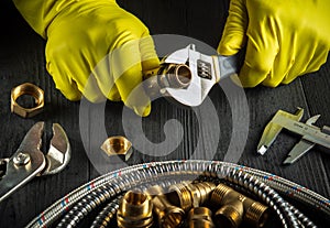 Master plumber connects the brass fittings to the faucet with an adjustable wrench. Close-up of a foreman gloved hands while