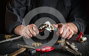 Master plumber connects the brass fittings to the faucet with an adjustable wrench. Close-up of a foreman is hands while working