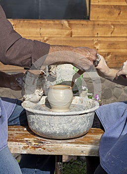 Master Potter teaches how to sculpt a clay pot under a potter's wheel.