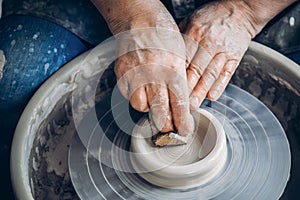 Master on potter wheel makes clay dishes. Workshop place