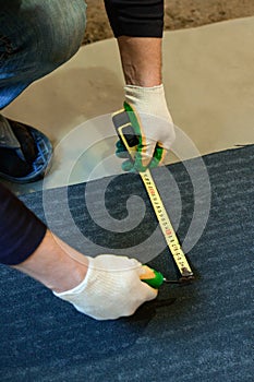 The master prepares a bituminous tape for installation, protection of a floor against moisture.