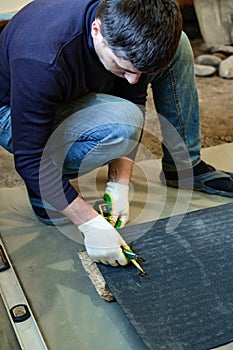 The master prepares a bituminous tape for installation, protection of a floor against moisture.
