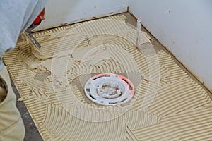 master puts on the floor adhesive for tiling