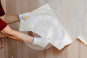 The master removes old wallpaper from the wall. Repair of apartments