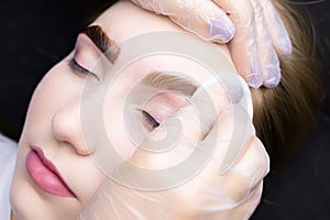 The master removes the remnants of paint from the eyebrows of the model with a cotton sponge