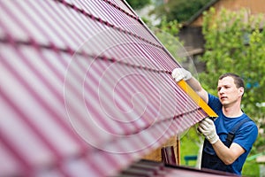 Master on repair of roofs makes measurements tool photo