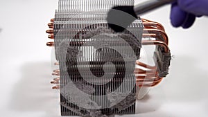 The master repairman with a brush cleans dust from the heatsink of the PC central processor cooling. Home pc maintenance