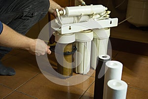 The master replaces dirty filters in the home water purification system. Human hands, filter, membrane