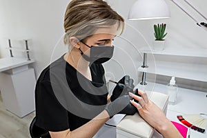 Master in rubber gloves covering nails with varnish in a beauty salon. Perfect nail manicure process