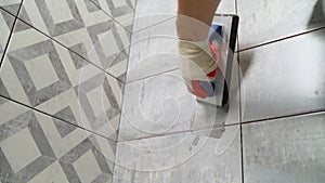 The master rubs the tile with a spatula. Repair and wall tiling. The master rubs the seams of the tiles with black putty