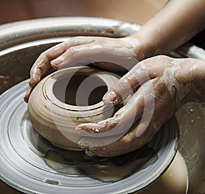 Master's hands mold a jug on a potter's wheel