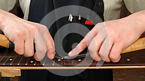 Luthier removes the frets of the guitar neck photo