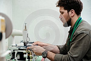 A master is sewing details for future product made of genuine leather