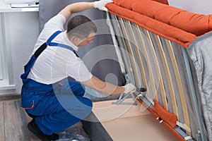 The master of sofa and bed maintenance repairs the mechanisms of the storage box