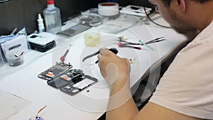 Master soldering microchip for mobile phone and using syringe with rosin.