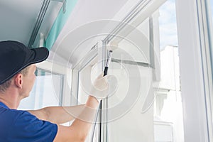 The master straightens the plastic window with a rubber mallet, after installing it