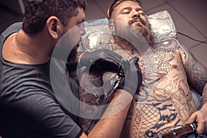 Master tattooist makes tattoo pictures in a workshop studio