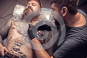 Master tattooist makes tattoo pictures in a workshop studio