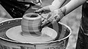 Master teaching kid to creating on the pottery wheel. Craftsman`s hands and child