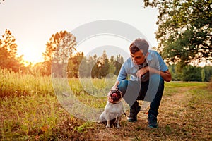Master walking and hugging pug dog in autumn forest. Happy puppy sitting on grass. Dog love