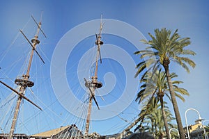 The masts of an ancient sailing ship with lowered sails in front of the blue sky and bright sunlight