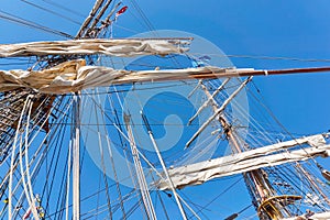 Masts of an old sailing ship with rolled up white sails