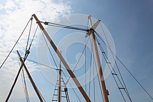 Masts with rigging, block and tackle, old sailing vessels silhouetted against a blue sky