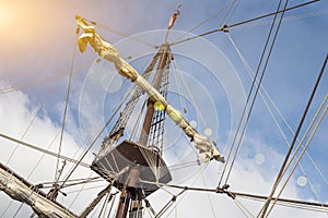 Masts and rigging of old pirate ship on background of cloudy blue sky