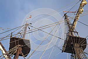 Masts and rigging of old pirate ship on background of cloudy blue sky