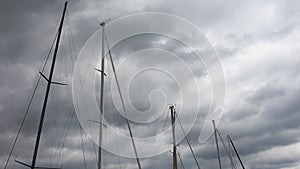 Masts of sailing boats moving slowly in the wind in front of a sky