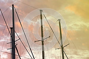 Masts of a yacht without sails against the background of a sunset cloudy sky