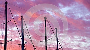 Masts of a yacht without sails against the background of a sunset cloudy sky