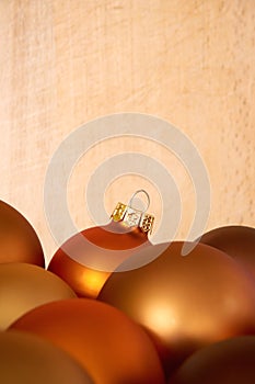 Mat bronze orange colored chtristmas balls in front of wooden background