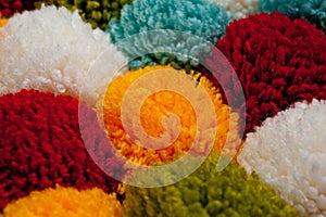 Mat of pompons made from multi-colored handmade yarn