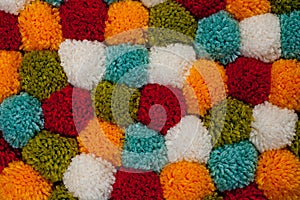 Mat of pompons made from multi-colored handmade yarn