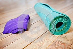 Mat for yoga rolled-up on wooden floor