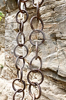 Matal chains pairs hanging by the side of a rock side