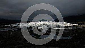 Matanuska Glacier lit up by sunlight on a dark evening.