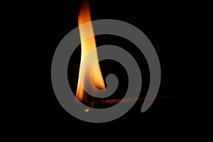 Match burning in the dark with bright orange flame against black background